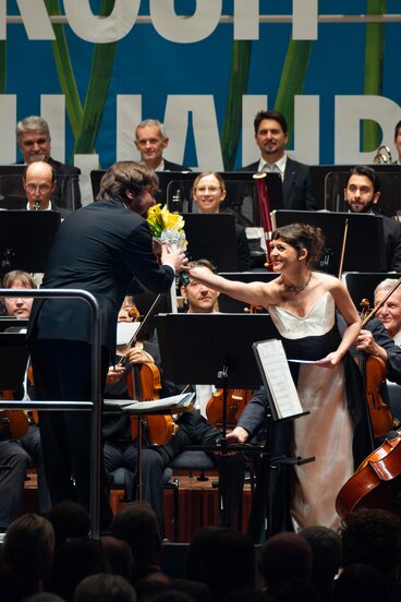 Neujahrskonzert 2026: Dirigent Ainārs Rubiķis Moderatorin Juliana Haider | © WE FEEL